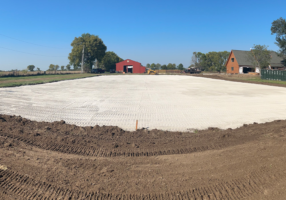 Textured white gravel foundation with red barn distant.