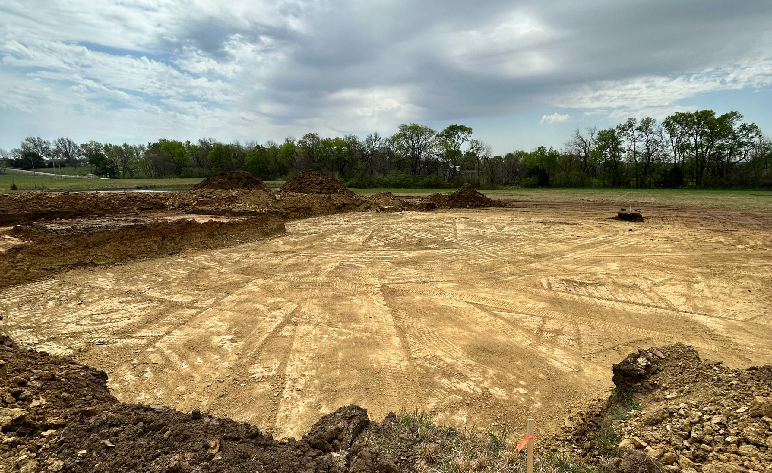 Excavation pit showing dirt and tracks with mounds of soil.