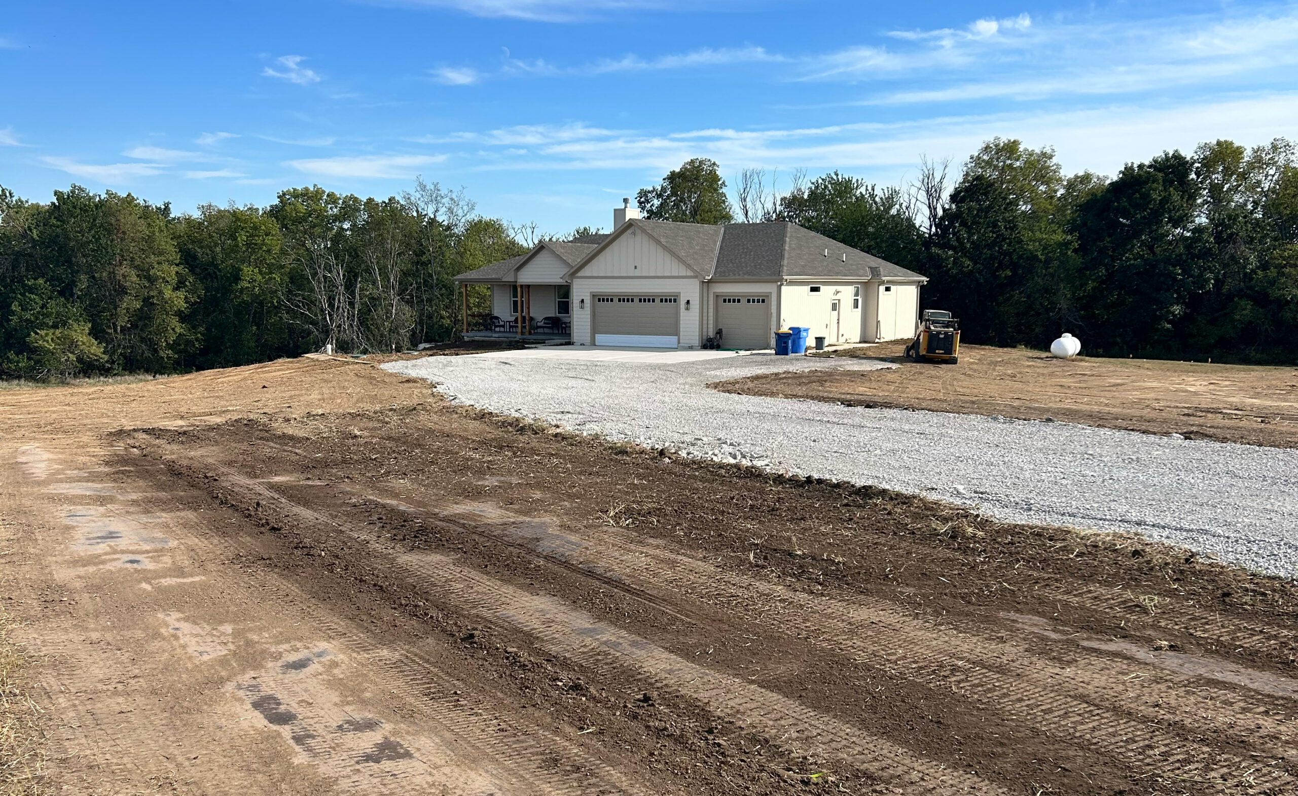 Grassy lawn leading to cleared ground among trees.