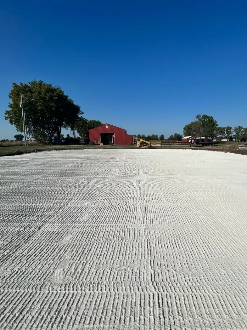Textured white gravel foundation with red barn distant.